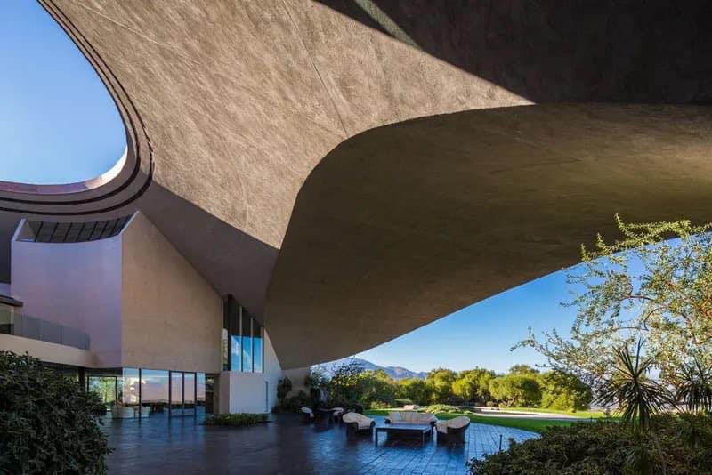 A curved white concrete building sitting low over still water