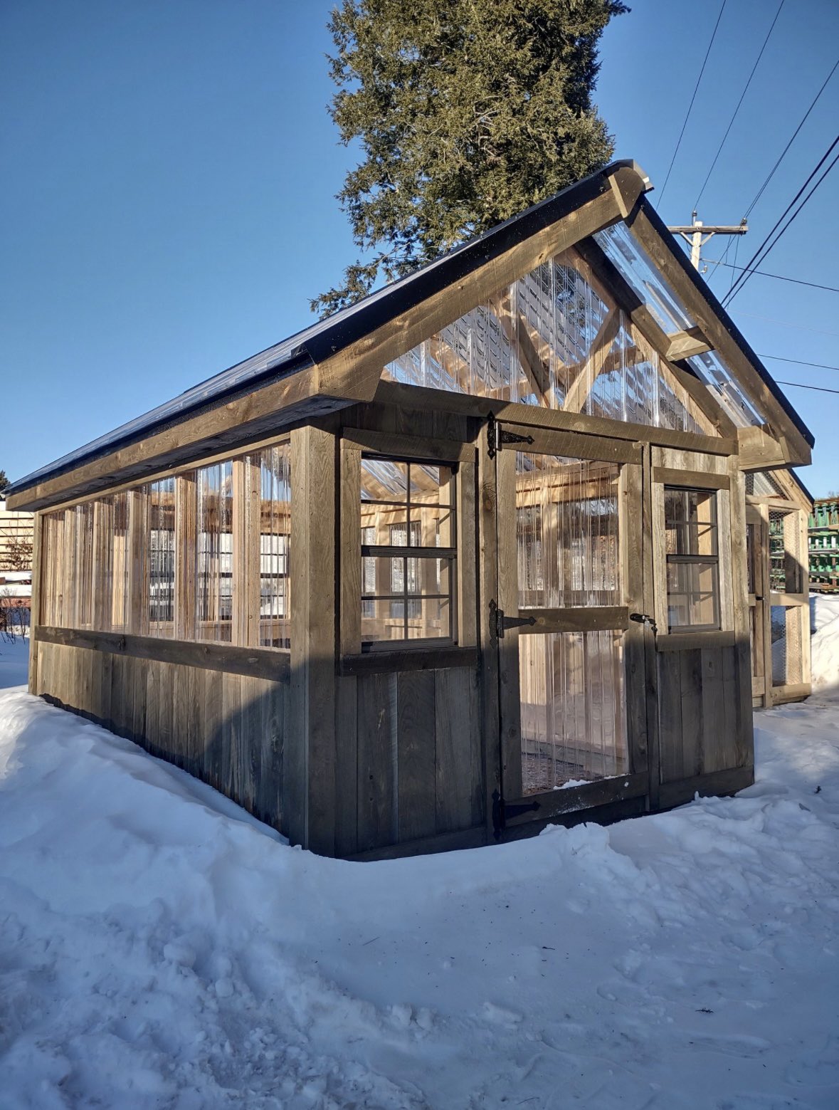 A timber-framed cabin with tall windows, standing in deep snow