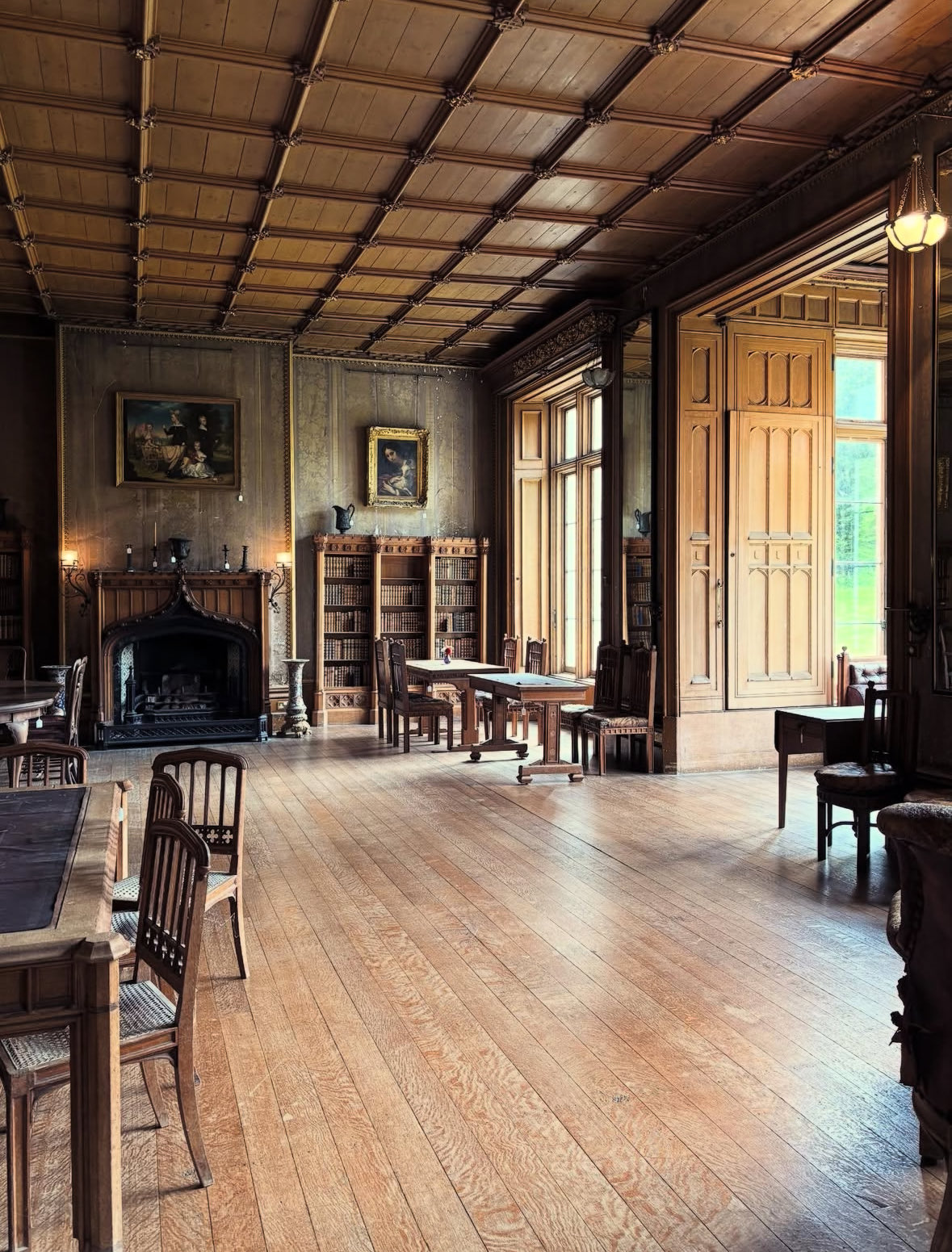 A long timber room with a stone fireplace, plank floor and shuttered doors